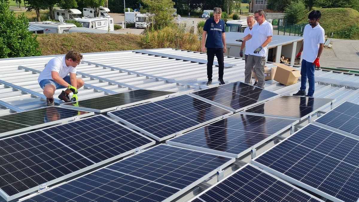 Mehrere Männer montieren eine Photovoltaik-Anlage auf einem Dach der Therme Bad Wörishofen