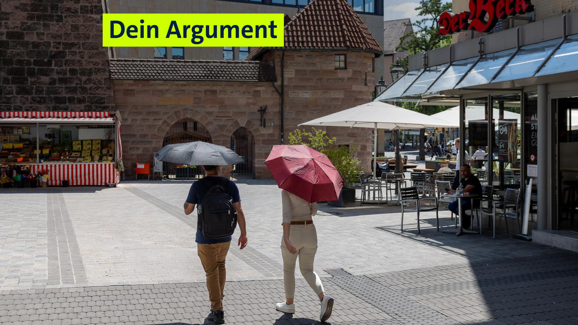 (Symbolbild) Zwei Personen mit Sonnenschirmen gehen bei starker Sonneneinstrahlung über den Platz vor dem Weißen Turm in Nürnberg.