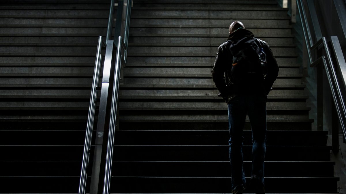 Ein Mann mit Glatze geht im Dunkeln eine Treppe hinauf, Berlin