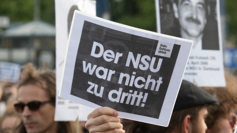 Demonstranten halten Schilder nach dem Urteil im NSU-Prozess in die Luft. "Der NSU war nicht zu dritt"(Archivbild)
