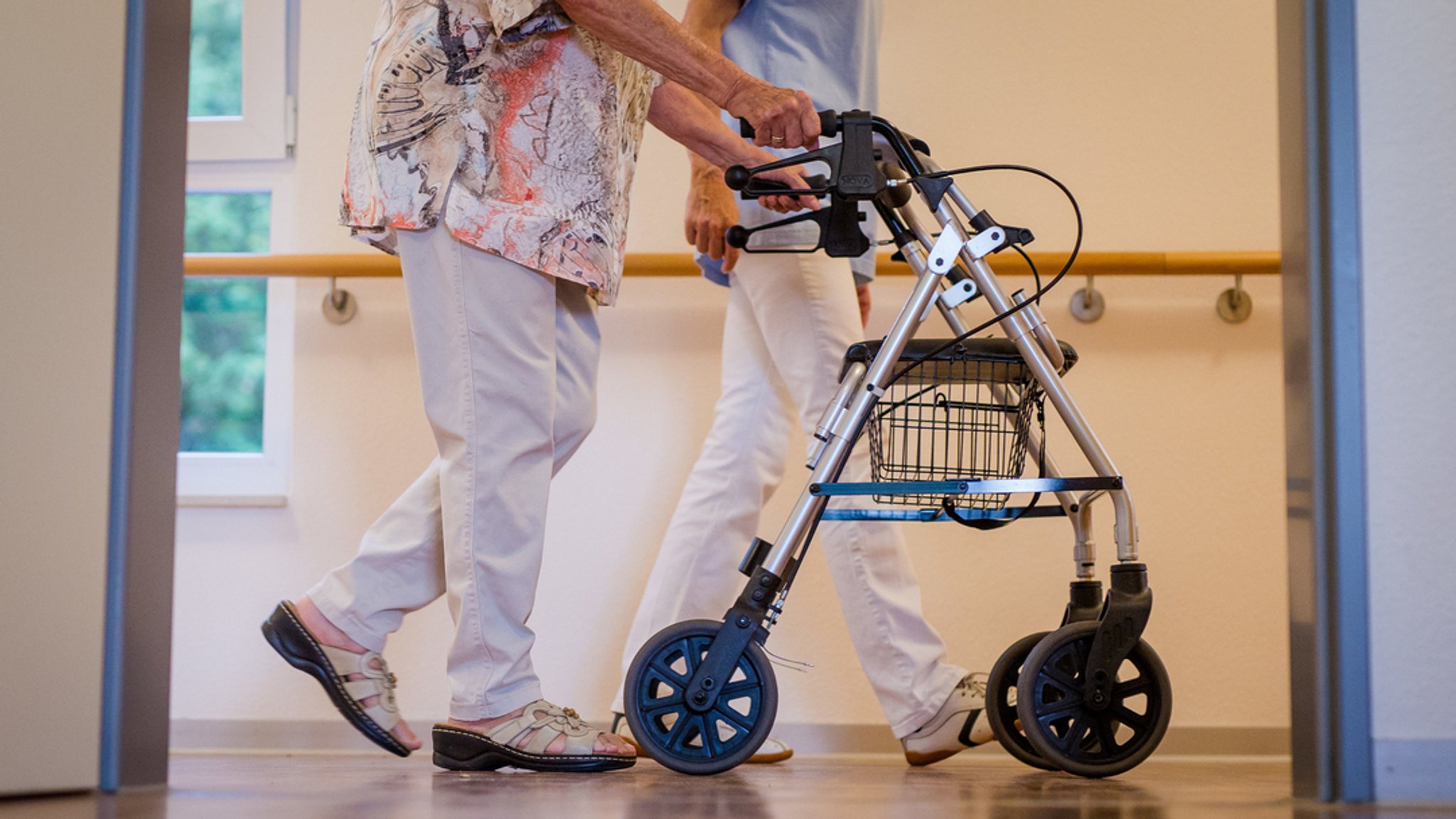 Frau mit Rollator läuft über Gang