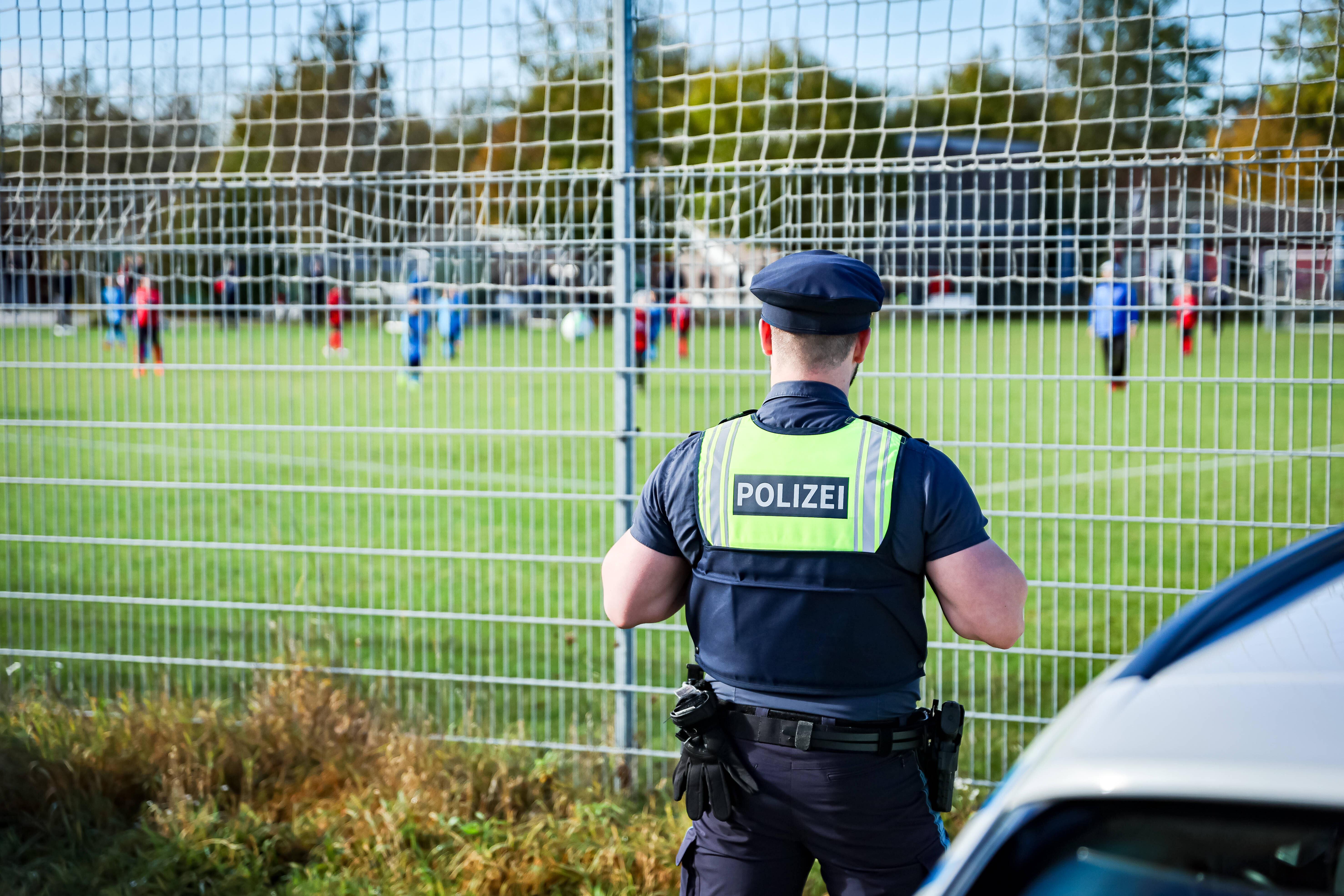 Ein Polizist beobachtet ein Amateur-Fußballspiel.