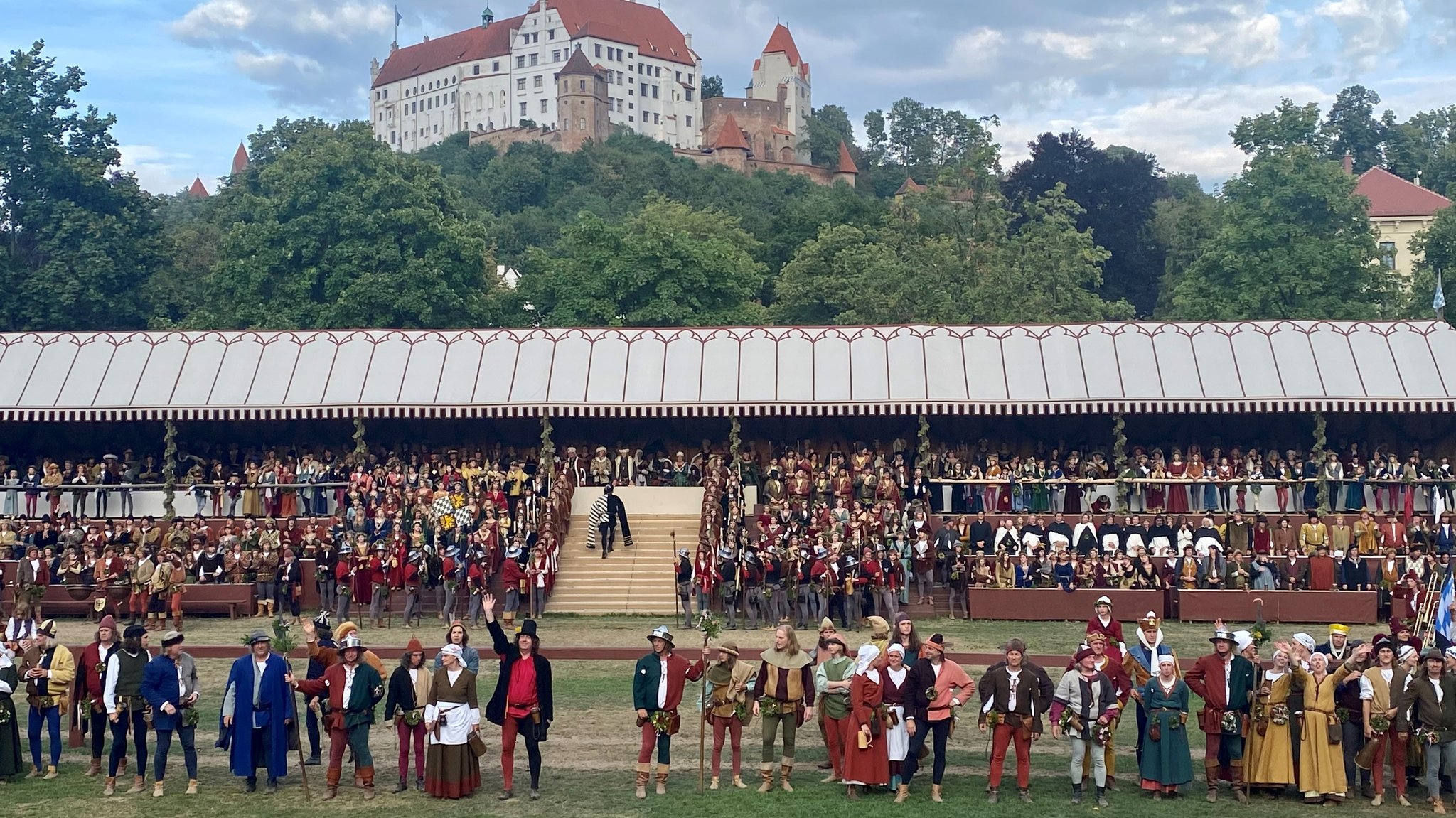 Schauspieler der Landshuter Hochzeit stehen in einer Reihe, einige winken.