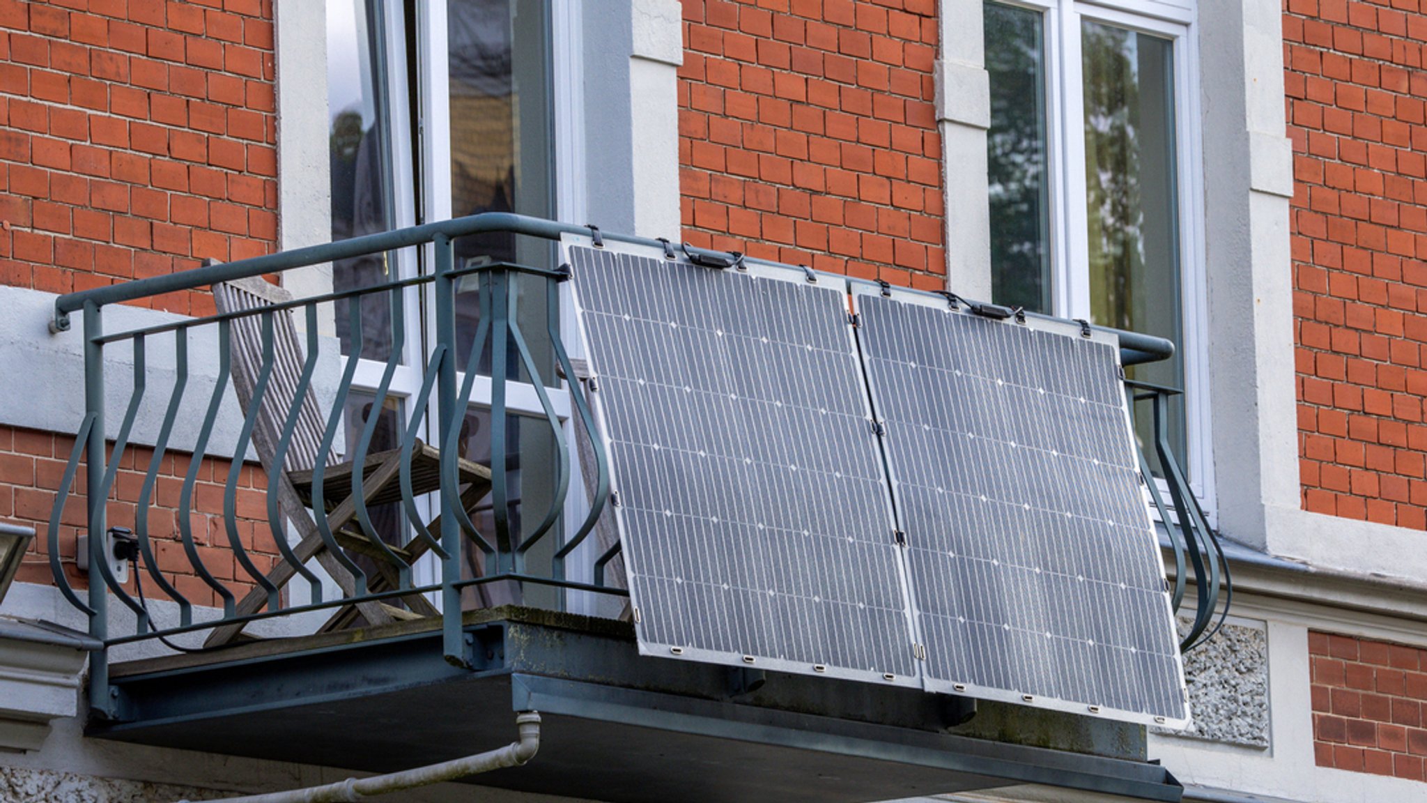 Solarmodule für ein sogenanntes Balkonkraftwerk hängen an einem Balkon.