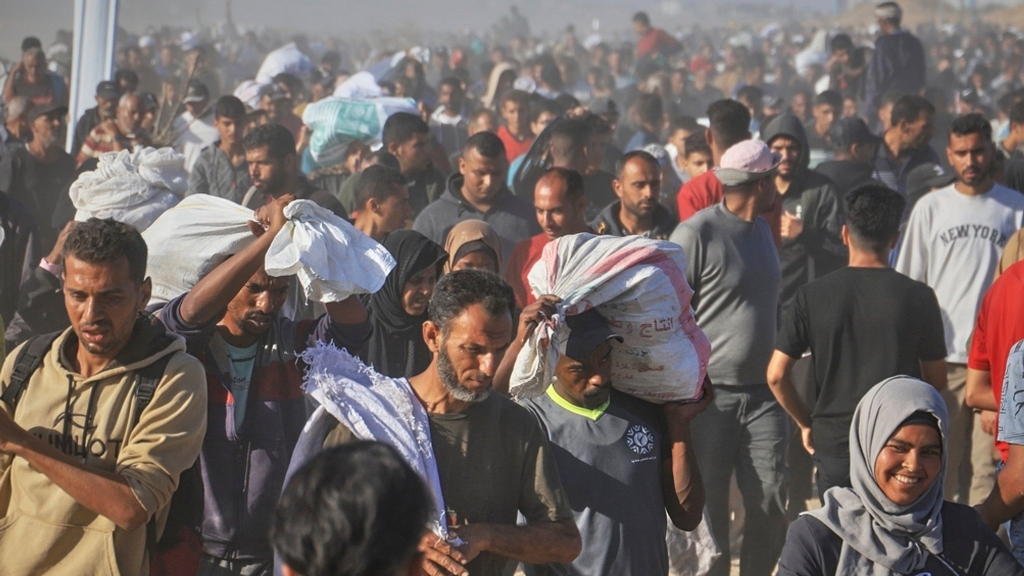 29.05.2025, Palästinensische Gebiete, Rafah: Palästinenser tragen in Rafah im südlichen Gazastreifen Kisten und Taschen mit Lebensmitteln und humanitären Hilfspaketen, die von der Gaza Humanitarian Foundation, einer von Israel anerkannten und von den USA unterstützten Organisation, geliefert wurden. 