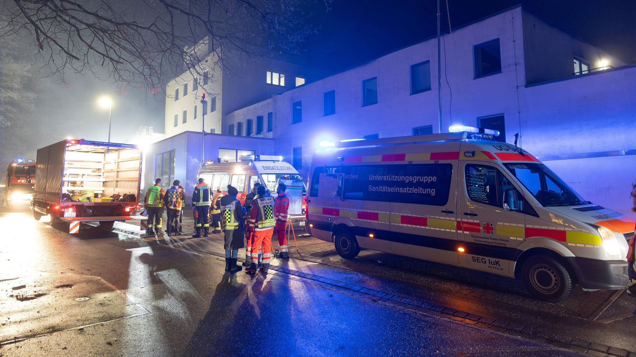 Einsatzkräfte stehen im Dunkeln vor dem Krankenhaus.