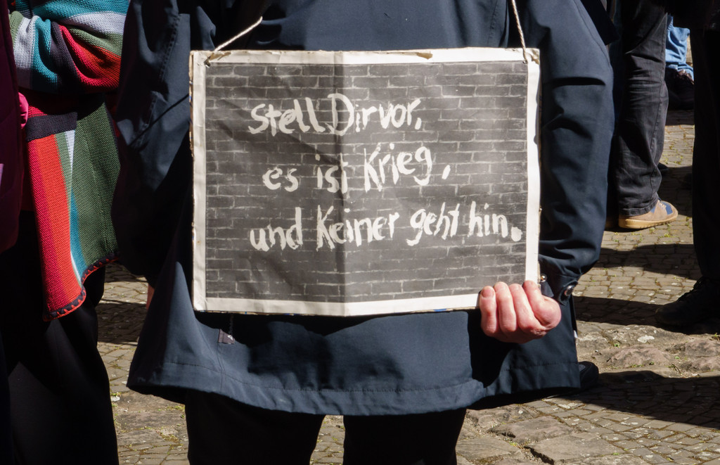 Symbolbild: Eine Demonstrantin mit einem Plakat "Stell Dir vor, es ist Krieg, und keiner geht hin" 