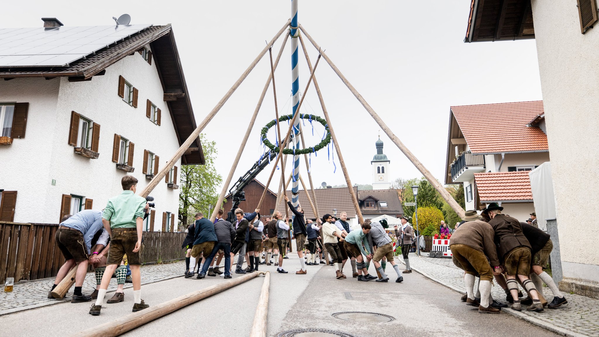 Mitglieder der Burschenschaft Perchting stellen einen Maibaum am Dorfplatz auf