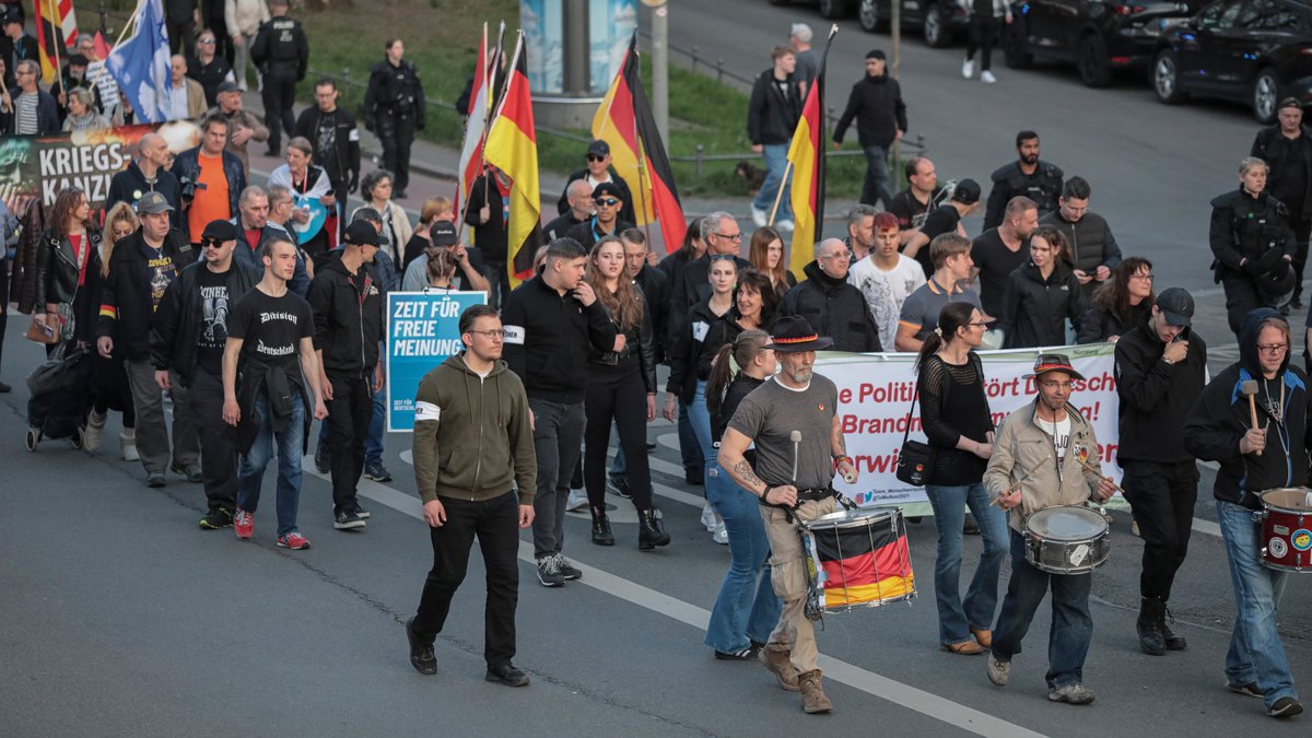 Die Demonstrationsteilnehmer schwenken bei einem Umzug Fahnen durch die Luft. 