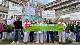 Krankenhaus-Mitarbeiter halten Transparente in die Höhe, auf denen steht unter anderem: "Wir lassen nicht locker, wir fordern kommunale Trägerschaft".  | Bild:BR/Richard Padberg 