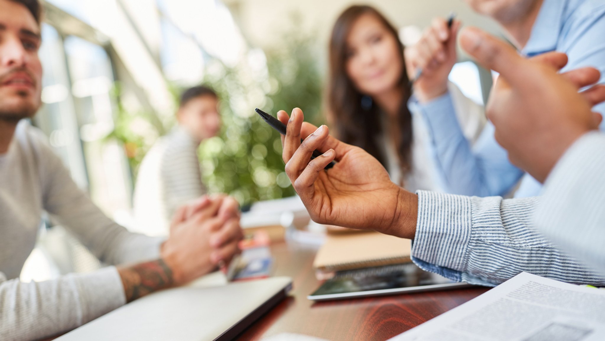 Junge Menschen bei einem Meeting mit Laptops und Tablets. KI, Digitalisierung und demografischer Wandel verändern die Arbeitswelt, aber das Interesse an Weiterbildung ist in Deutschland nicht hoch genug.