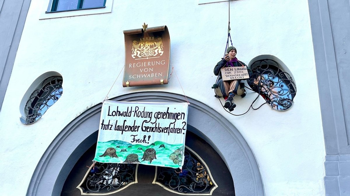 Die Fassade der Regierung von Schwaben: Aktivisten haben ein Banner angebracht, auf dem steht:  Lohwald-Rodung trotz laufender Gerichtsverfahren? Frech!