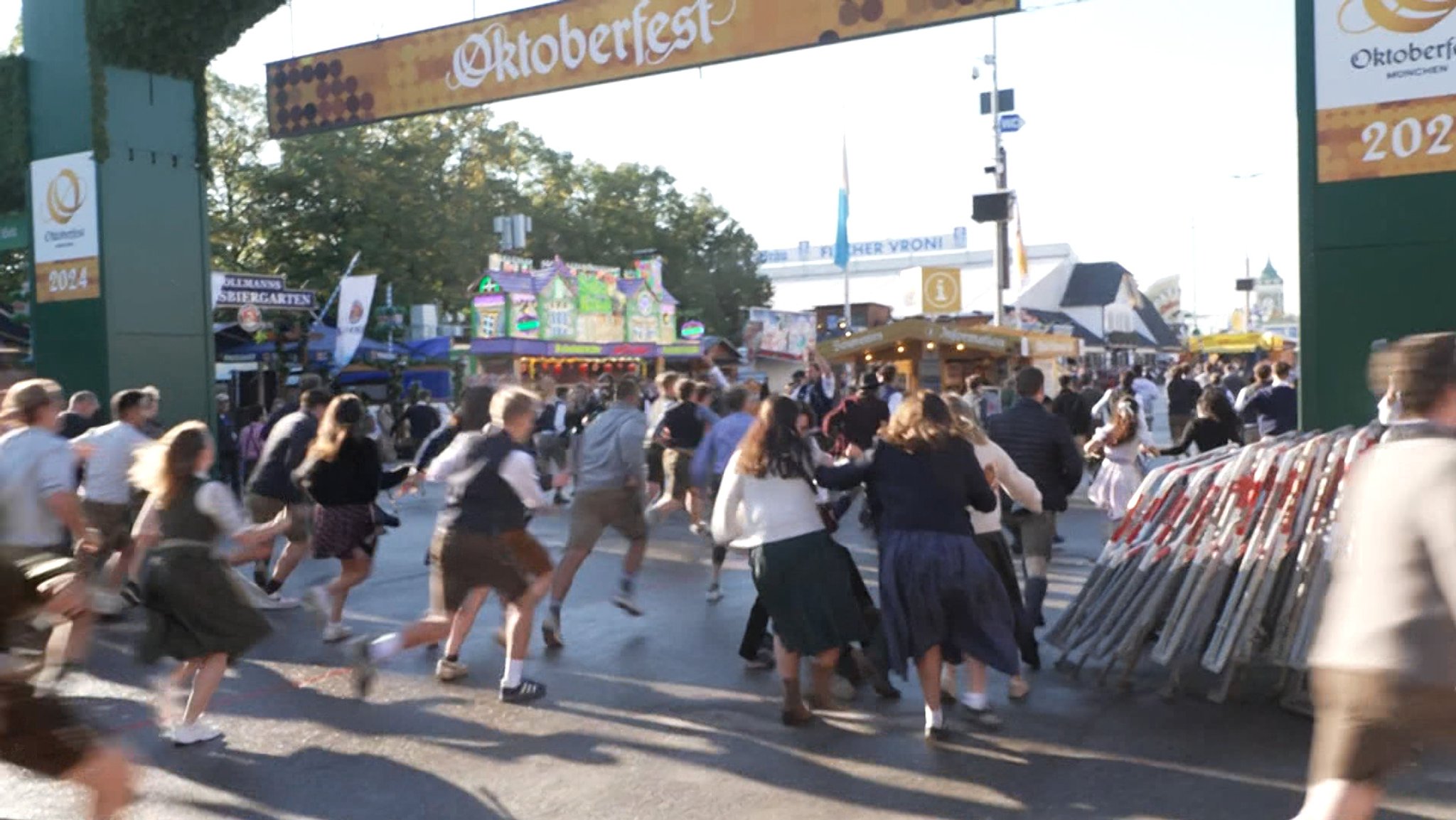 Viele Menschen, die meisten jung und in Tracht, rennen durch den Haupteingang aufs Oktoberfestgelände auf der Theresienwiese. 