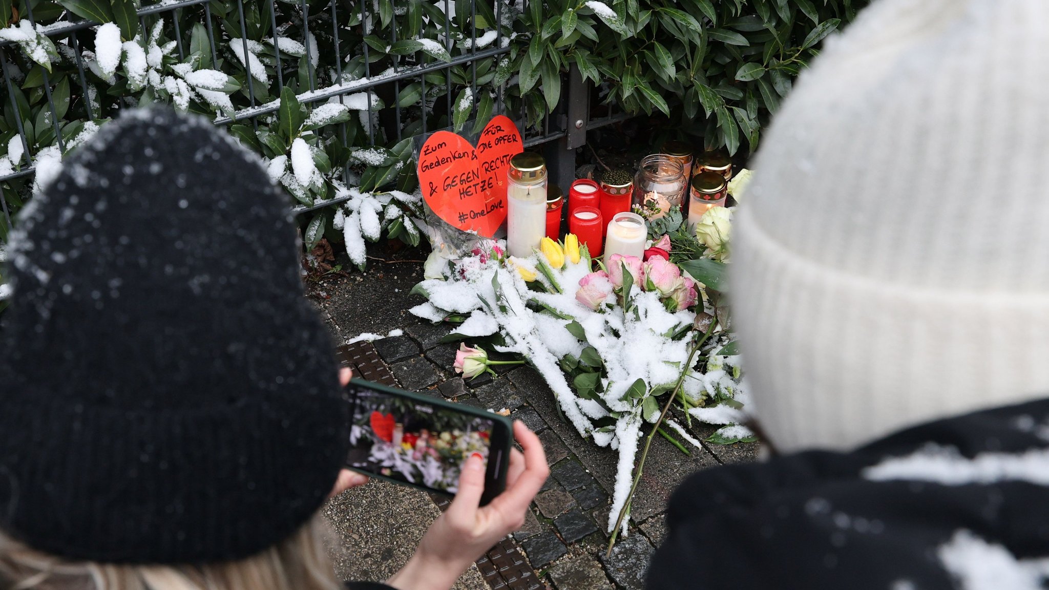 Ein Herz mit der Aufschrift "Zum Gedenken & für die Opfer 6 gegen rechte Hetze! #OneLove" liegt nahe der Stelle, wo am Vortag ein Auto in in eine Ver.di Demonstration gerast war, und wird von einer Frau fotografiert.