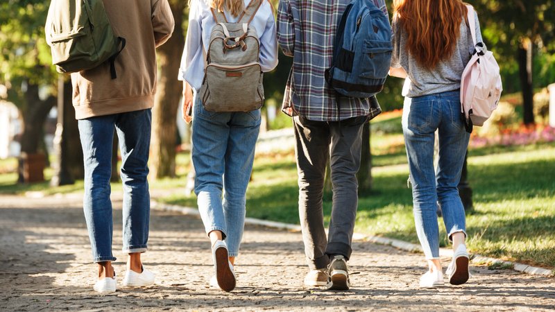 Rückenansicht einer Gruppe von Studierenden mit Rucksäcken, die im Freien auf dem Campus spazieren gehen. | Bild: stock.adobe.com/Drobot Dean Rückenansicht einer Gruppe von Studierenden mit Rucksäcken, die im Freien auf dem Campus spazieren gehen.