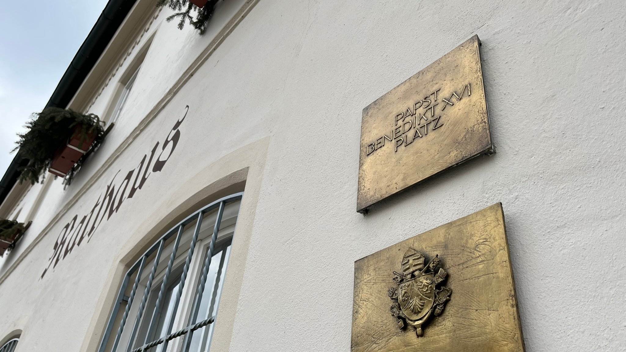 Am Rathaus sind goldene Plaketten angebracht. Auf der obersten steht: "Papst Benedikt XVI. Platz"