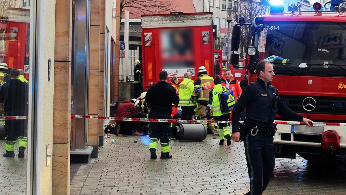 29.12.2023, Bayern, Passau: Einsatzkräfte von Feuerwehr und Rettungsdienst stehen in der Innenstadt am Einsatzort.
