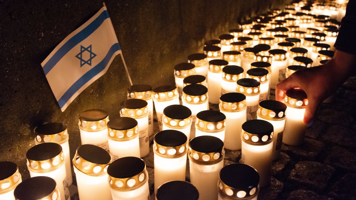 Symbolbild: Brennende Kerzen stehen vor einer kleinen Israel Flagge in Düsseldorf.