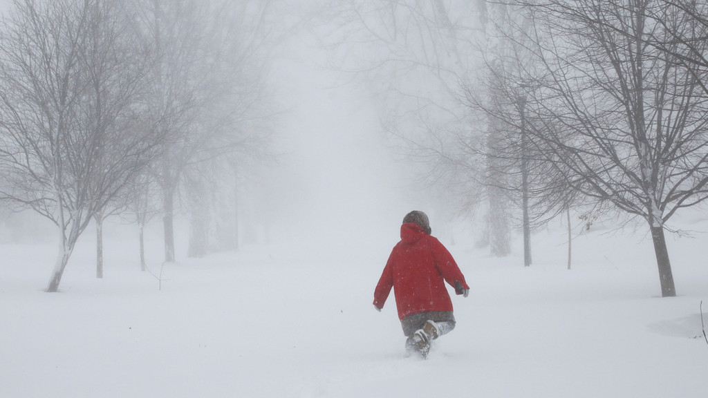 Ein Mensch läuft durch Schneemassen.