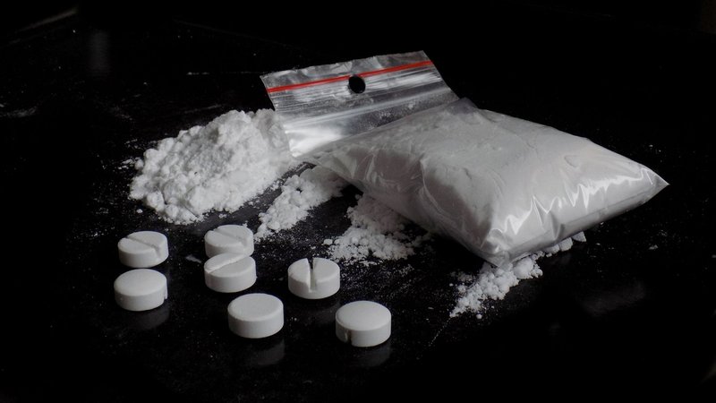Kokain und synthetische Pillen liegen auf einem schwarzen Tisch | Bild: stock.adobe.com/majo1122331 Kokain und synthetische Pillen liegen auf einem schwarzen Tisch