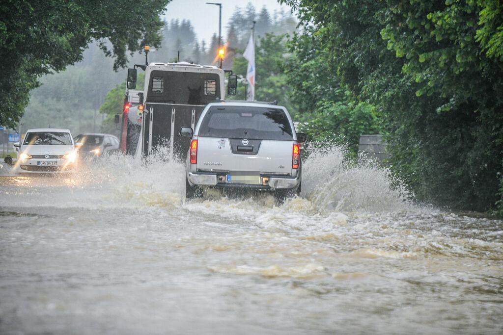 Babenhausen: Autos fahren durch Wasser auf einer überschwemmten Straße.