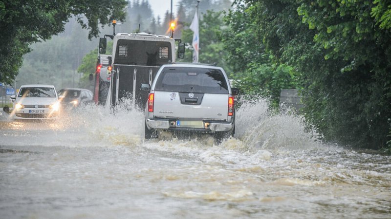 Babenhausen: Autos fahren durch Wasser auf einer überschwemmten Straße.