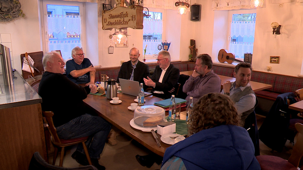 Menschen sitzen an einem Stammtisch. 