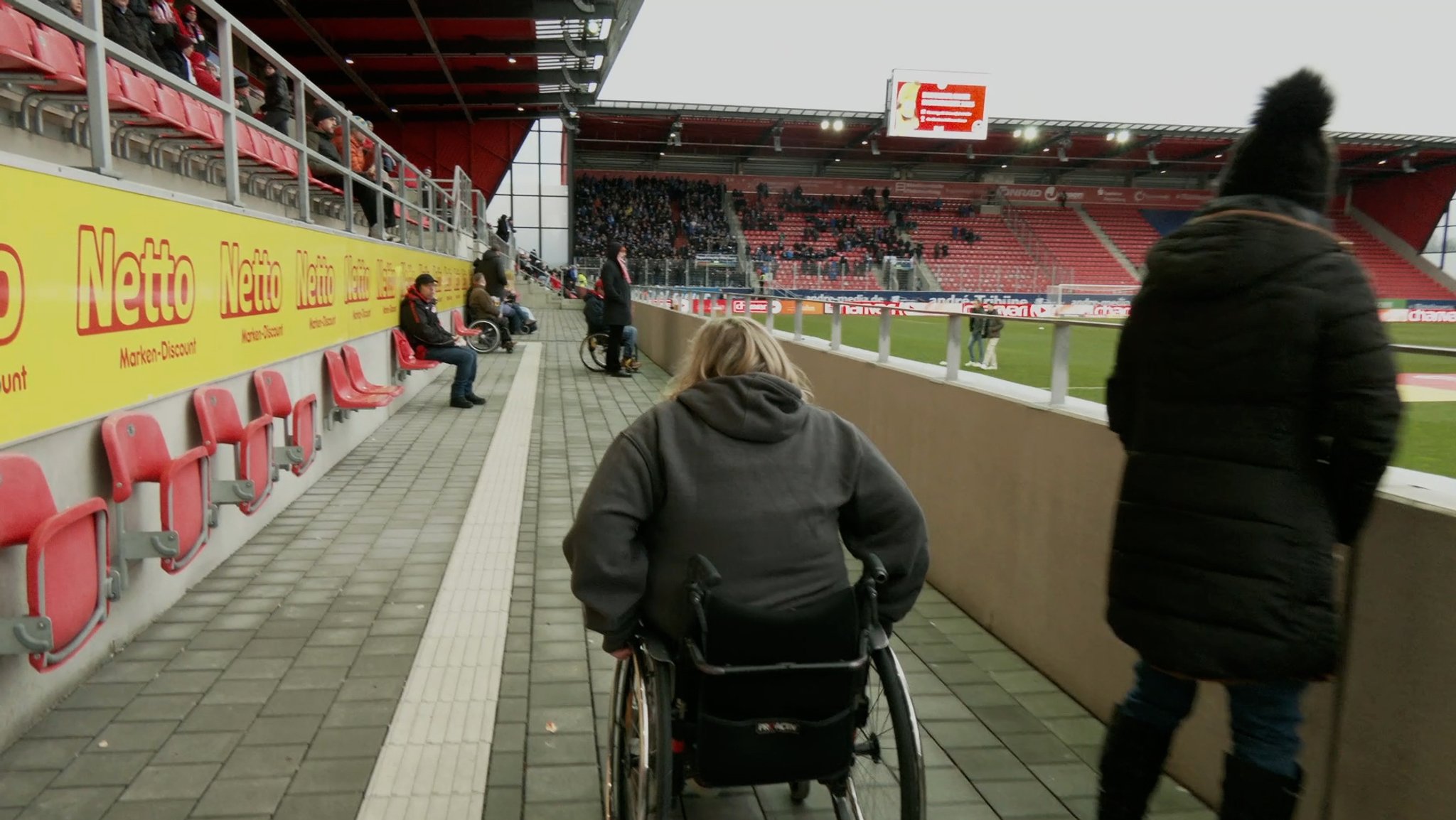 Eine Rollstuhlfahrerin ist im Jahnstadion in Regensburg unterwegs. 