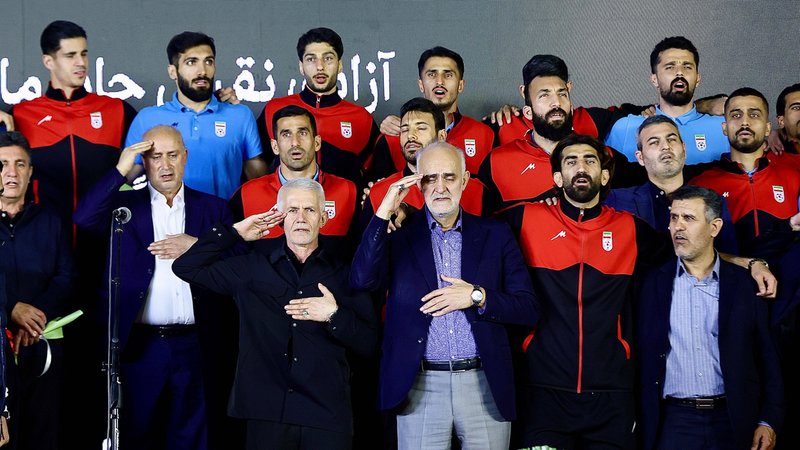 (Symbolbild) Spieler und Vertreter der iranischen Fußballnationalmannschaft stehen auf der Bühne, während sie den militärischen Gruß ausführen. | Bild: picture alliance / SIPA | Hossein/MEI (Symbolbild) Spieler und Vertreter der iranischen Fußballnationalmannschaft stehen auf der Bühne, während sie den militärischen Gruß ausführen.