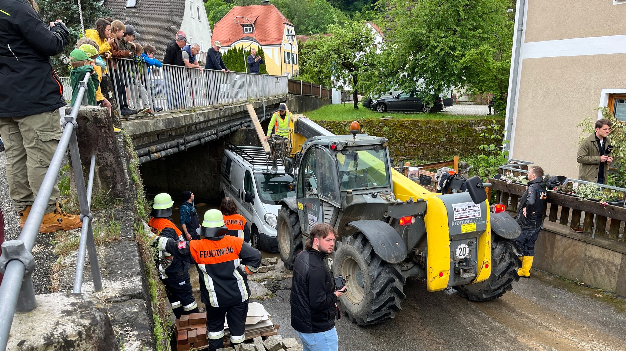 Der Lieferwagen der von den Fluten mitgerissen und an der Brücke hängengeblieben war, wird mit schwerem Gerät herausgezogen