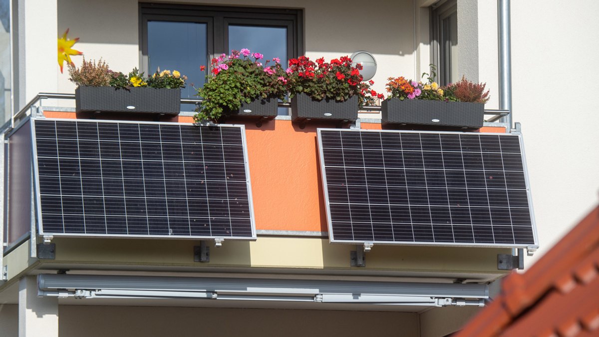 Solarmodule für ein sogenanntes Balkonkraftwerk hängen an einem Balkon. 