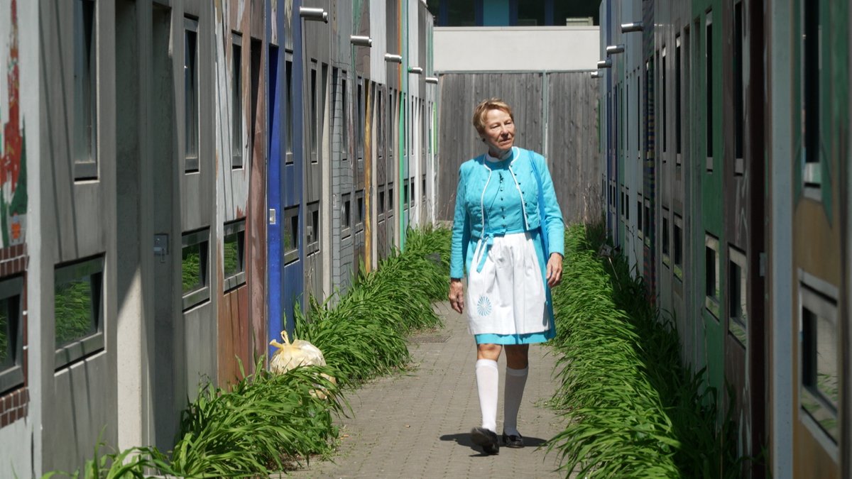Bruni Hülle in ihrem Hostessen-Drindl beim Spazierengehen im Studentendorf