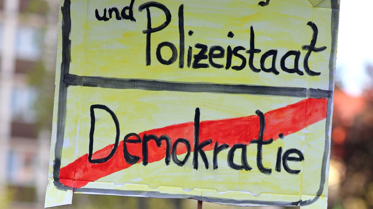 Schild mit Aufschrift "Überwachungsstaat und Polizeistaat? Demokratie".