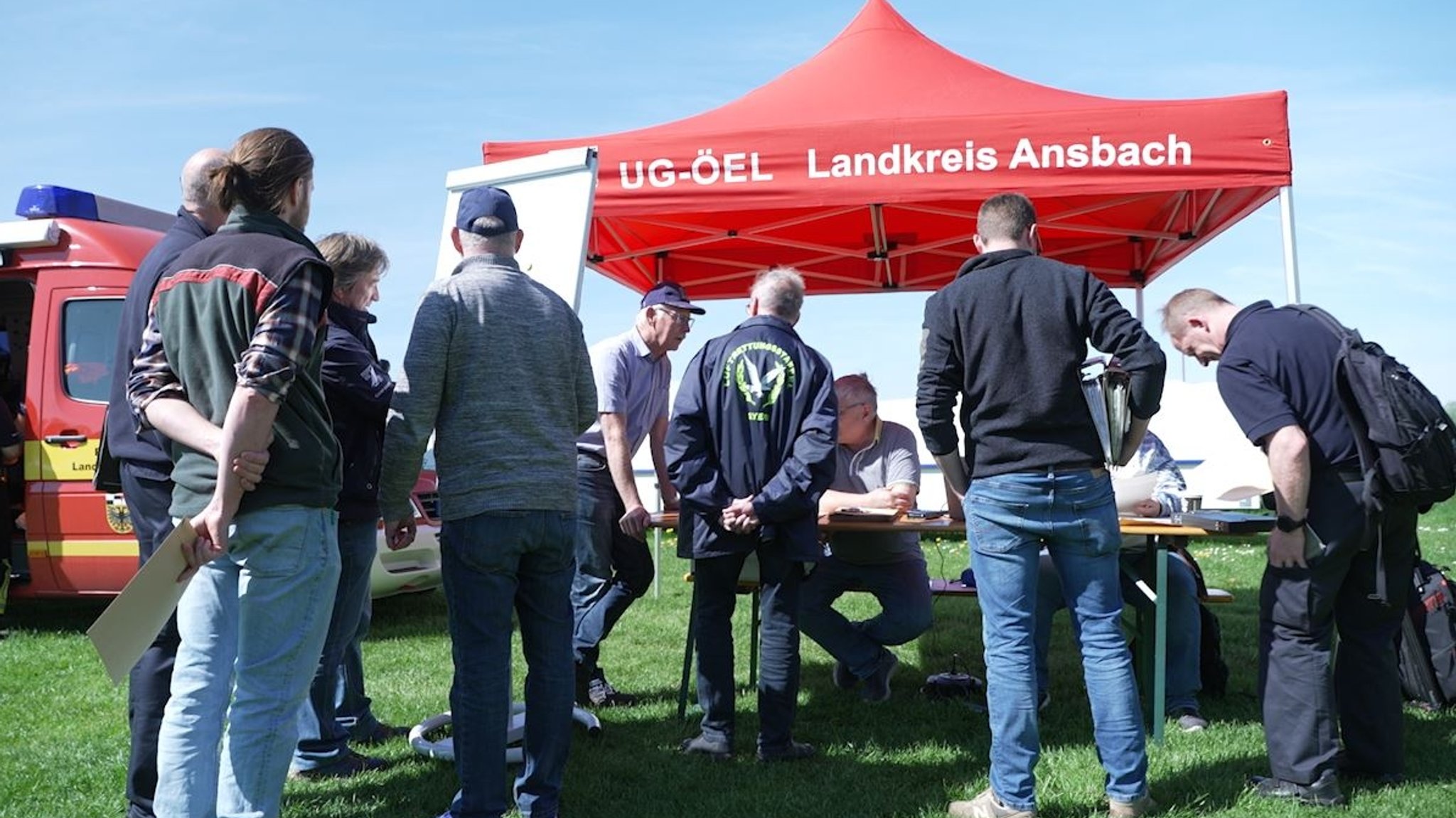 Menschen stehen vor einem Schreibtisch im Freien 