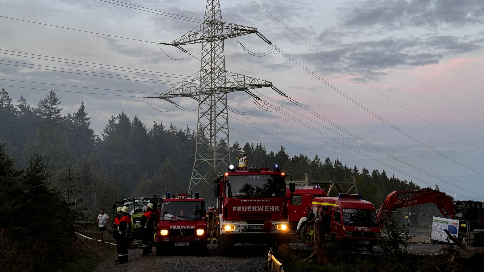 Feuerwehrautos stehen neben einem Strommast.