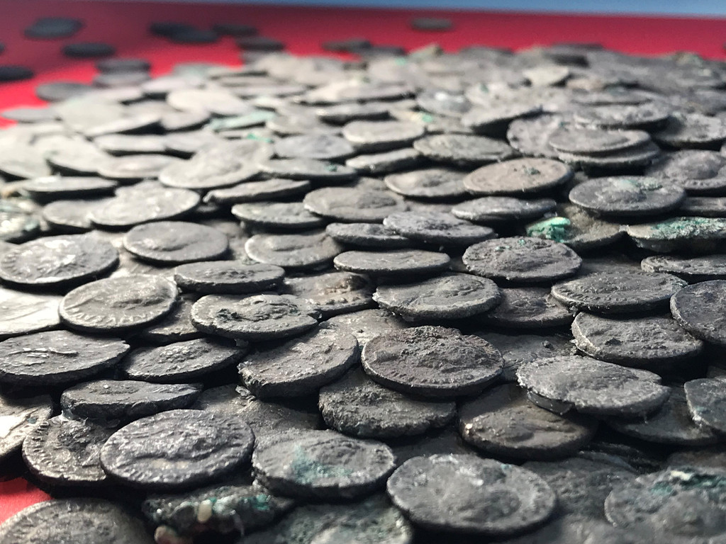 Römische Silbermünzen liegen auf einem roten Tuch. 