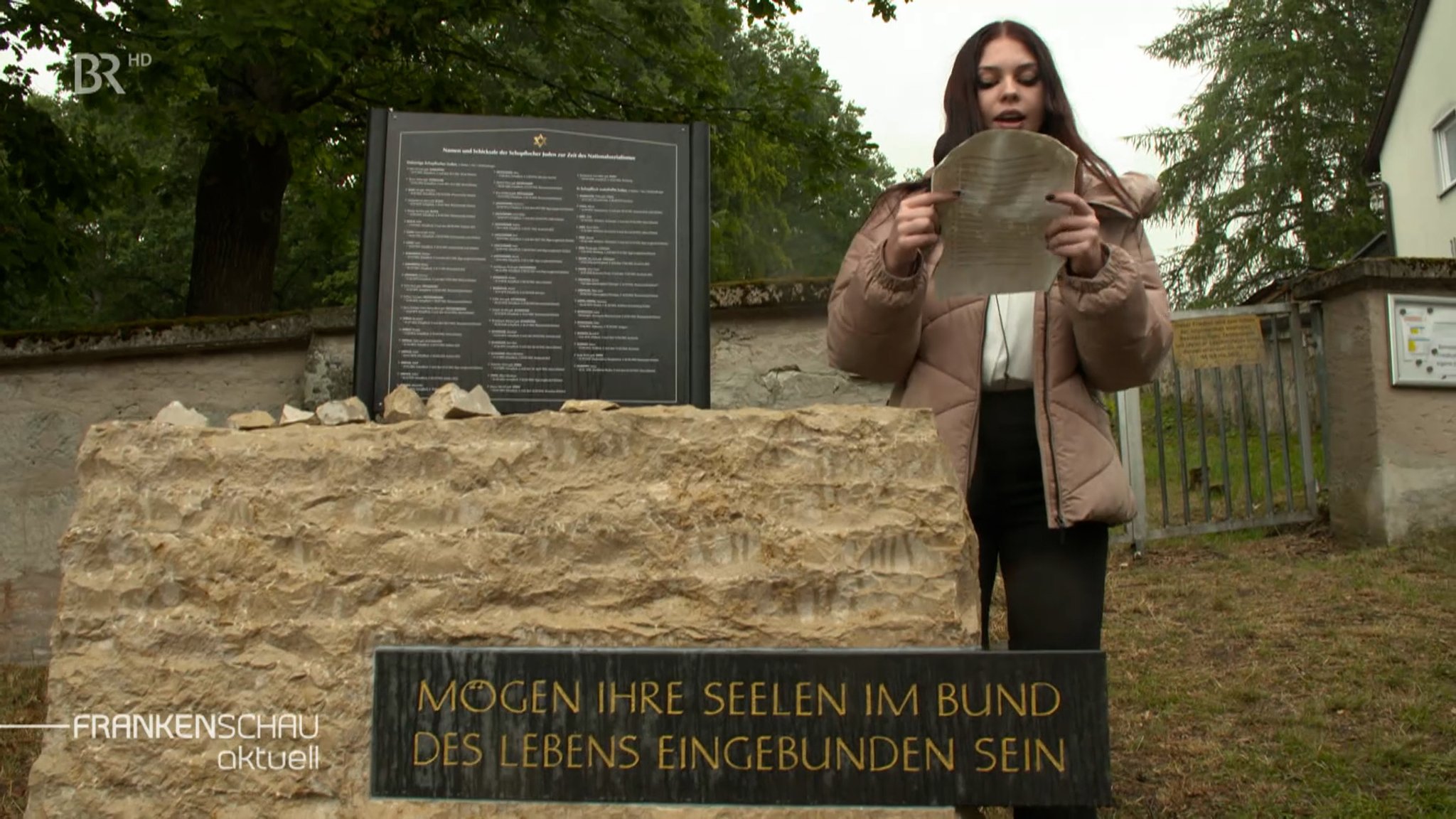 Schülerin liest etwas neben dem Gedenkstein und der Gedenktafel vor.