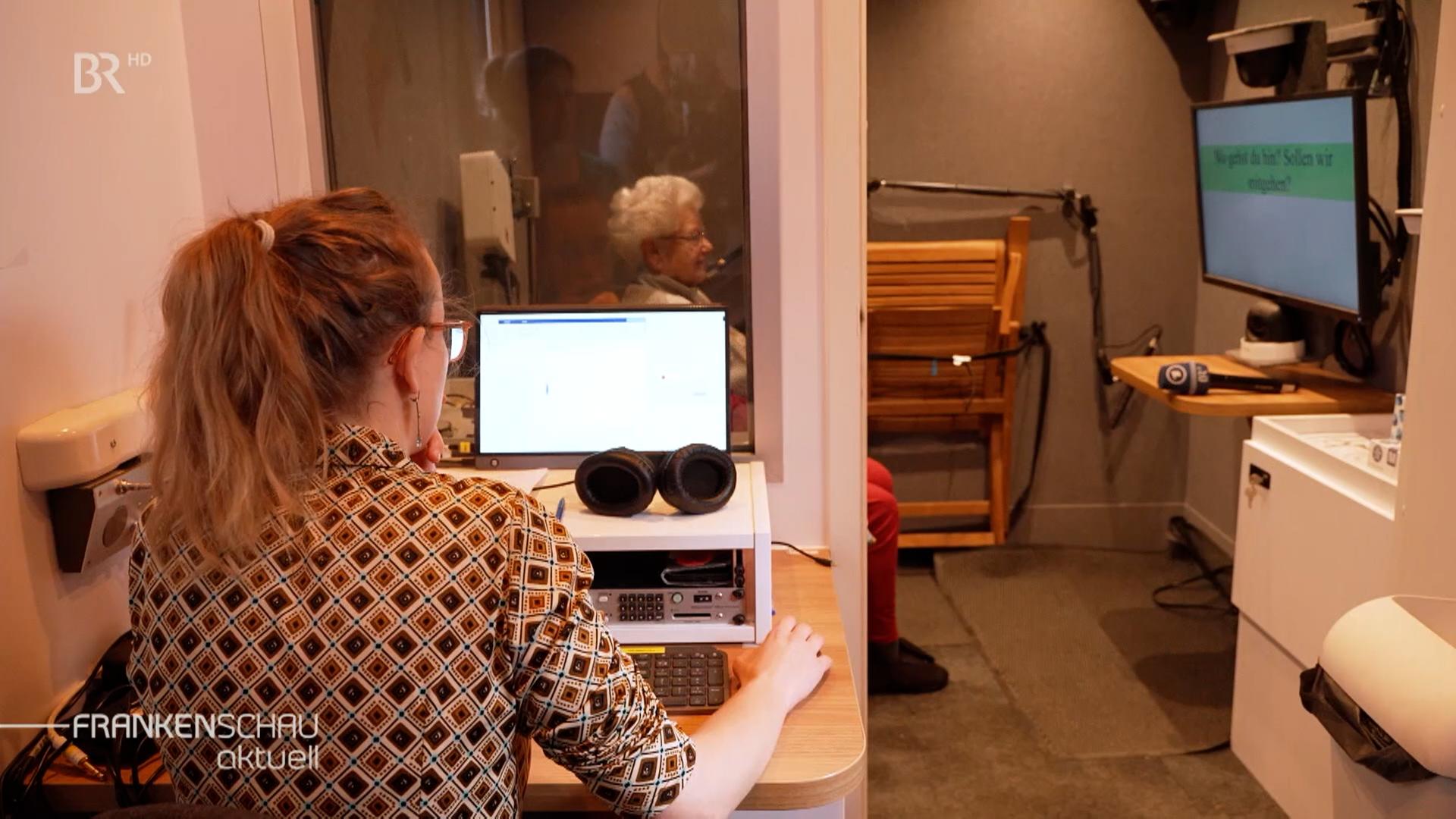 Eine Seniorin spricht gerade in einem Forschungsmobil in ein Mikrophon. 