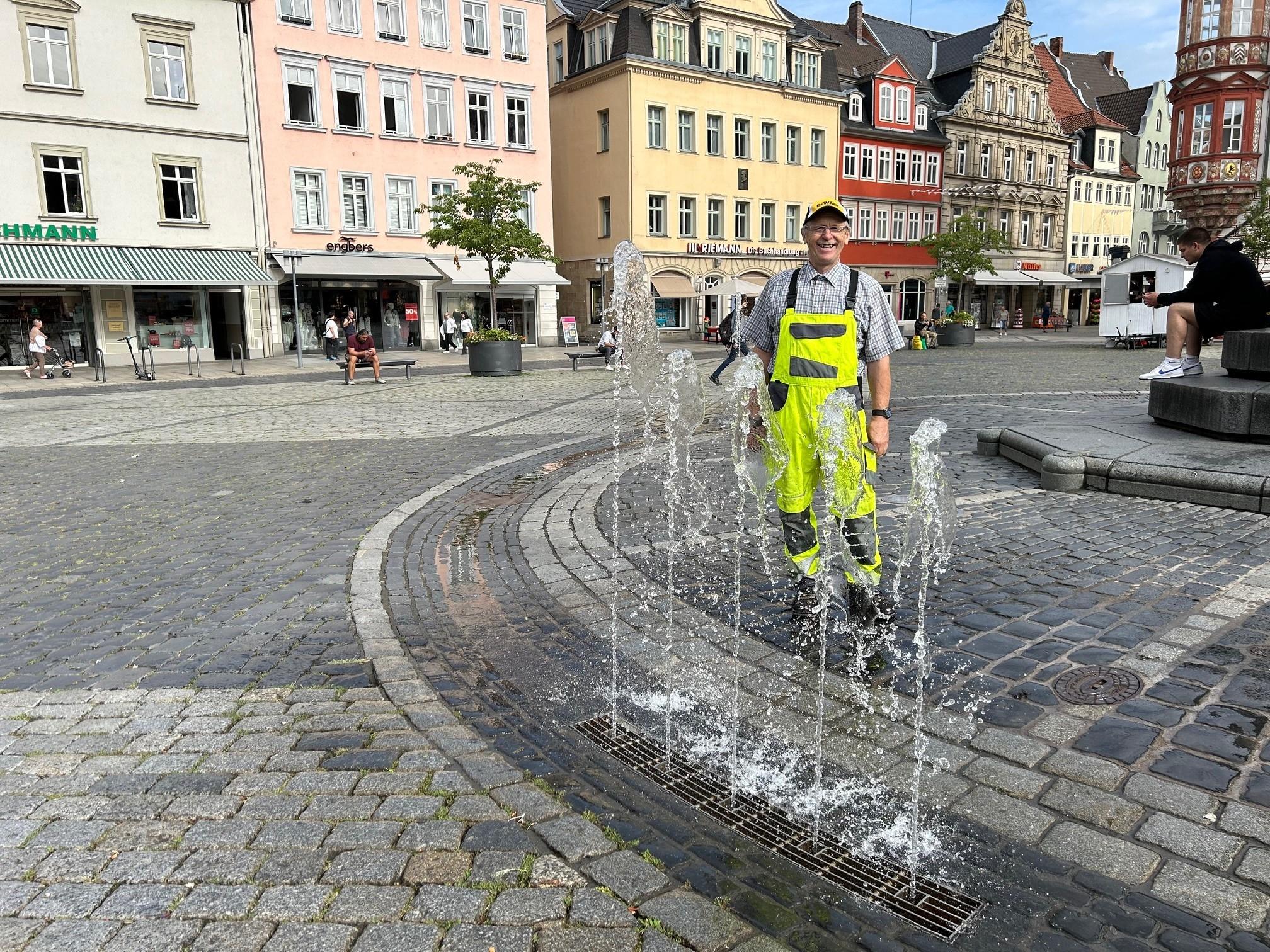 Ein Mitarbeiter der Stadt Coburg steht vor dem Brunnen am Coburger Marktplatz, der wieder sprudelt