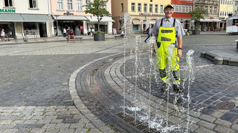 Ein Mitarbeiter der Stadt Coburg steht vor dem Brunnen am Coburger Marktplatz, der wieder sprudelt | Bild: BR24 / Andi Ebert Ein Mitarbeiter der Stadt Coburg steht vor dem Brunnen am Coburger Marktplatz, der wieder sprudelt