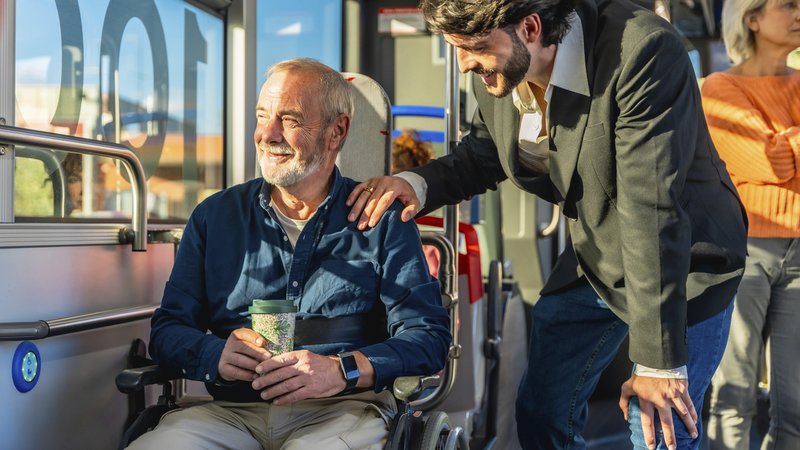 Junger Mann bietet einem lächelnden älteren Passagier im Rollstuhl Unterstützung an. Wer anderen Menschen hilft, erhöht die eigene Zufriedenheit, stärkt das Gefühl der Zugehörigkeit und hat eine positivere Sicht auf die Dinge. | Bild: picture alliance / imageBROKER | Unai Huizi Junger Mann bietet einem lächelnden älteren Passagier im Rollstuhl Unterstützung an. Wer anderen Menschen hilft, erhöht die eigene Zufriedenheit, stärkt das Gefühl der Zugehörigkeit und hat eine positivere Sicht auf die Dinge.