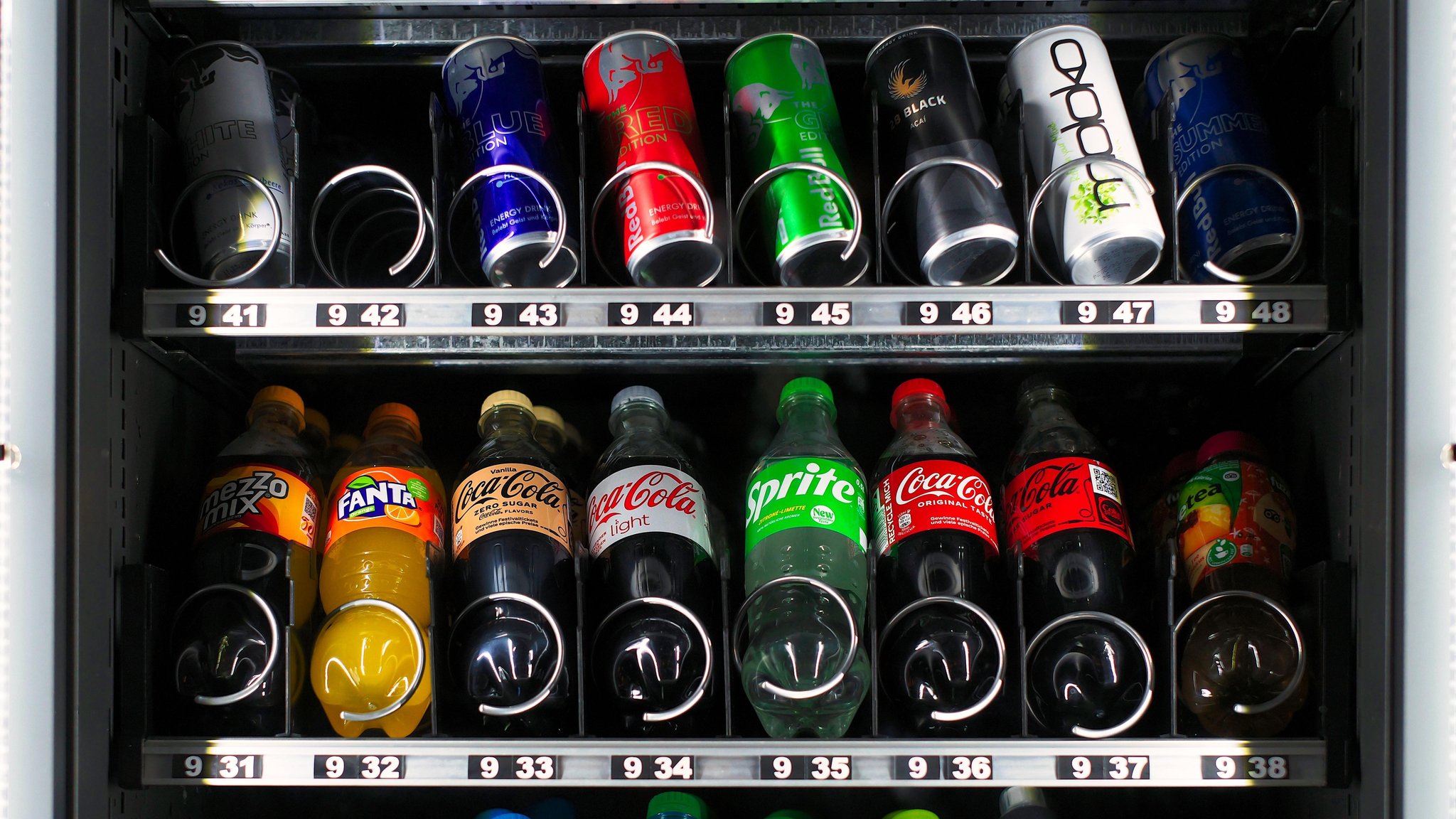 Softdrinks wie Cola und Limonaden liegen in einem Getränkekautomaten .