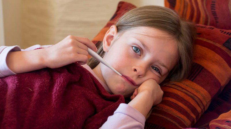 Ein Mädchen liegt mit Fieberthermometer im Mund auf der Couch. | Bild: picture alliance/Westend61/Sandra Rösch Ein Mädchen liegt mit Fieberthermometer im Mund auf der Couch.