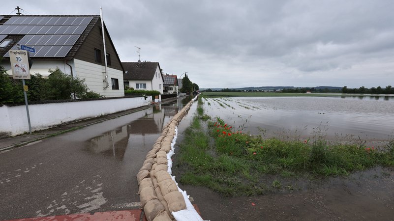 03.06.2024, Bayern, Asbach-Bäumenheim: Eine Barriere mit Sandsäcken soll ein Wohngebiet vor dem Hochwasser schützen.