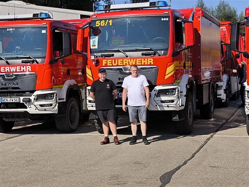 Die beiden Männer stehen vor einem Feuerwehrauto, das bereit für den Konvoi nach Polen ist. 
