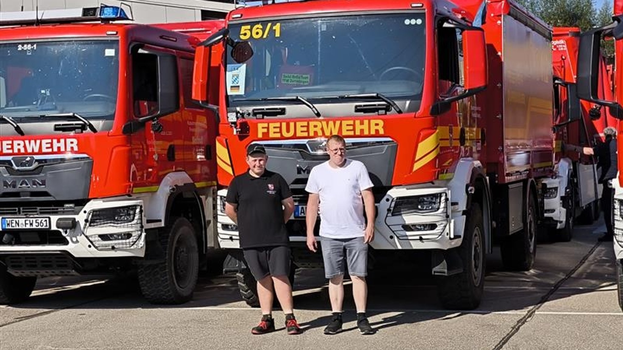 Die beiden Männer stehen vor einem Feuerwehrauto, das bereit für den Konvoi nach Polen ist. 