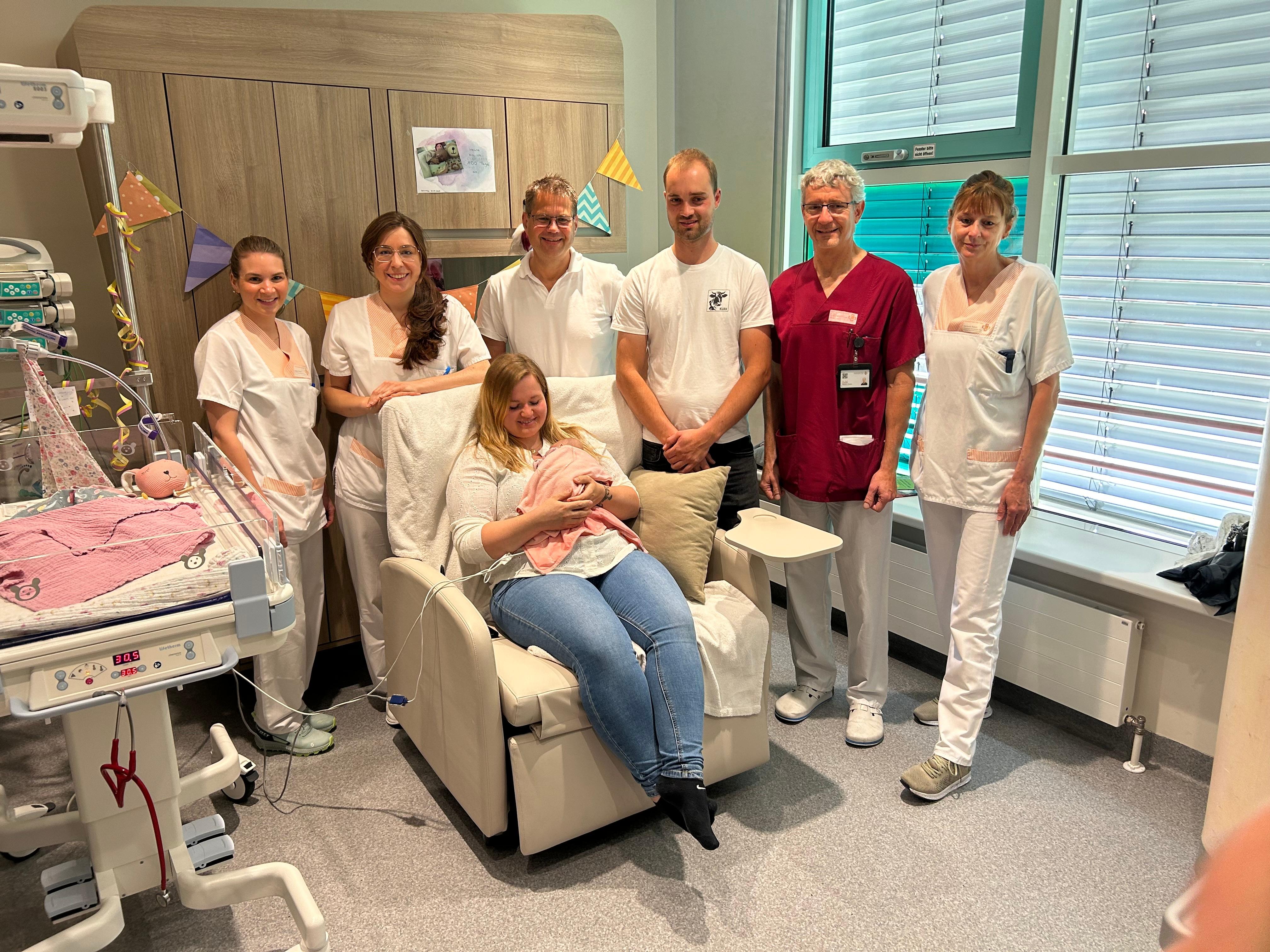 Menschen umringen eine Mutter und ihr frühgeborenes Baby