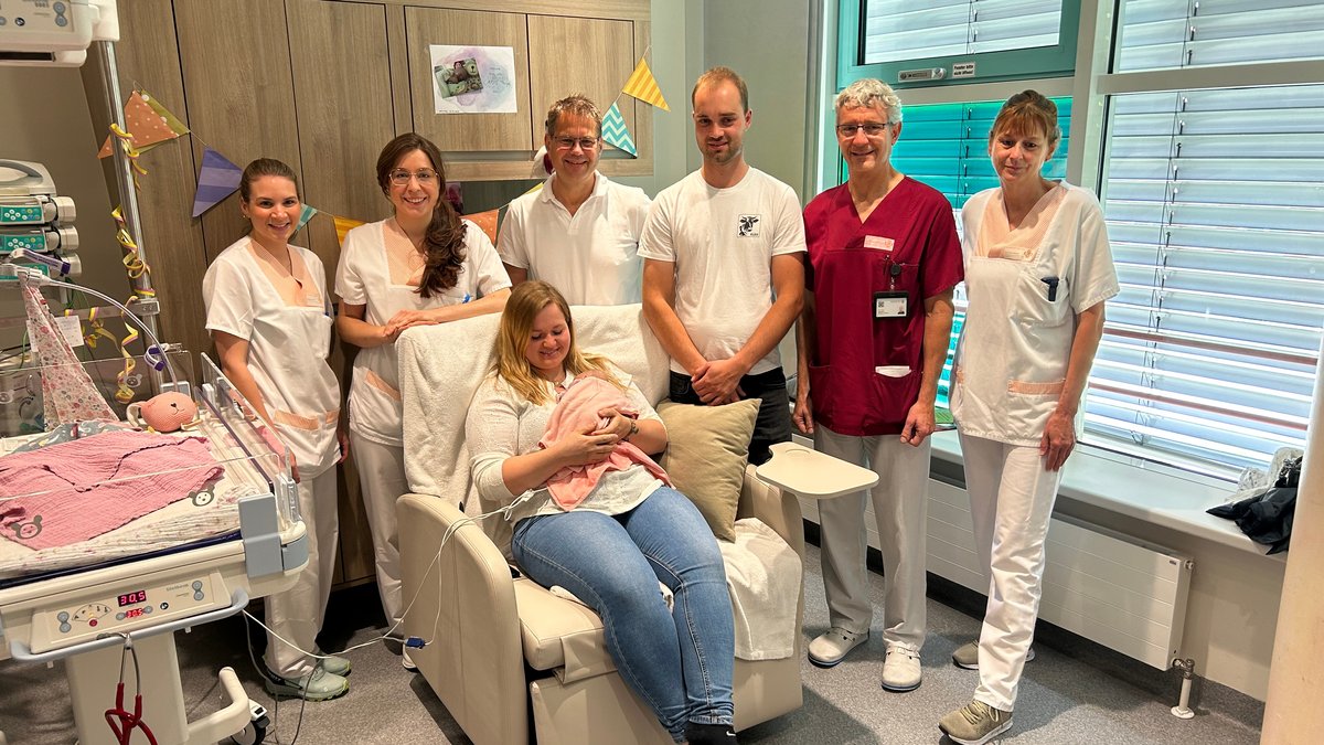 Menschen umringen eine Mutter und ihr frühgeborenes Baby