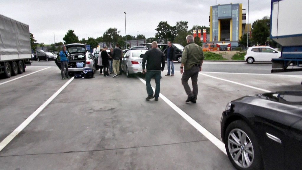 Polizisten in Zivil kontrollieren auf einen Parkplatz die Insassen eines Autos (Symbolbild)