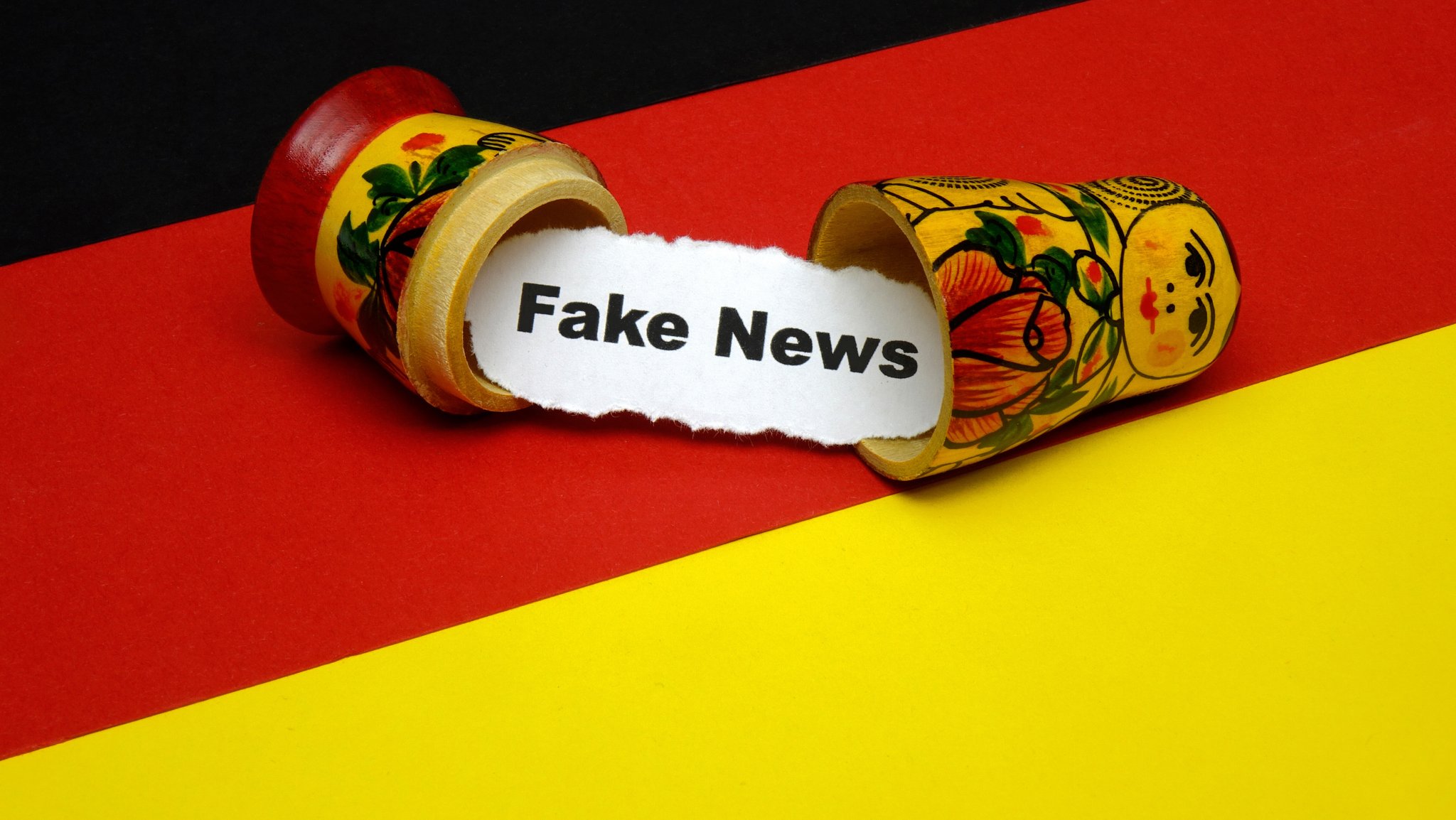 Eine geöffnete Matryoshka-Puppe, in der ein Zettel liegt, auf dem "Fake News" steht.